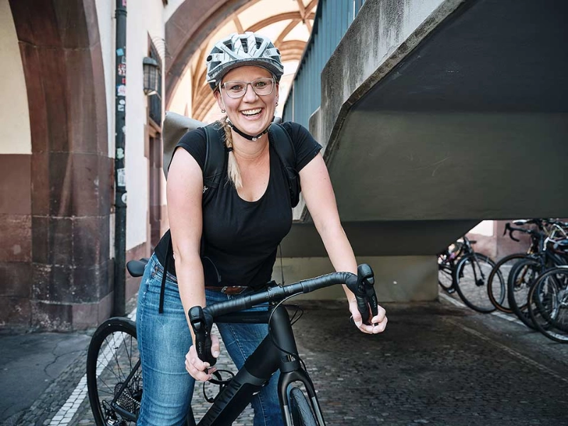 Eine lachende Frau auf ihrem schwarzen Fahrrad